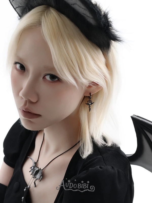 Black bat-wing pendant necklace, worn with other jewelry in a model portrait.