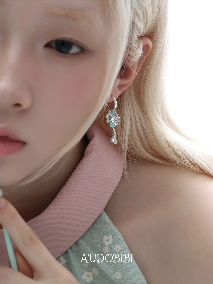 Lily Dreamlock Asymmetric Heart-Key Drop Earrings, shown worn by a model.