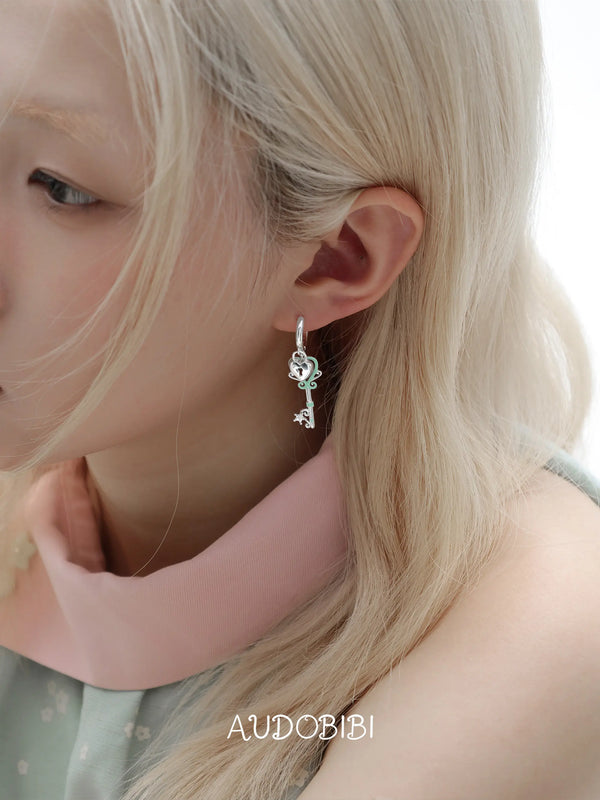 Lily Dreamlock Asymmetric Heart-Key Drop Earrings, shown worn by a model.