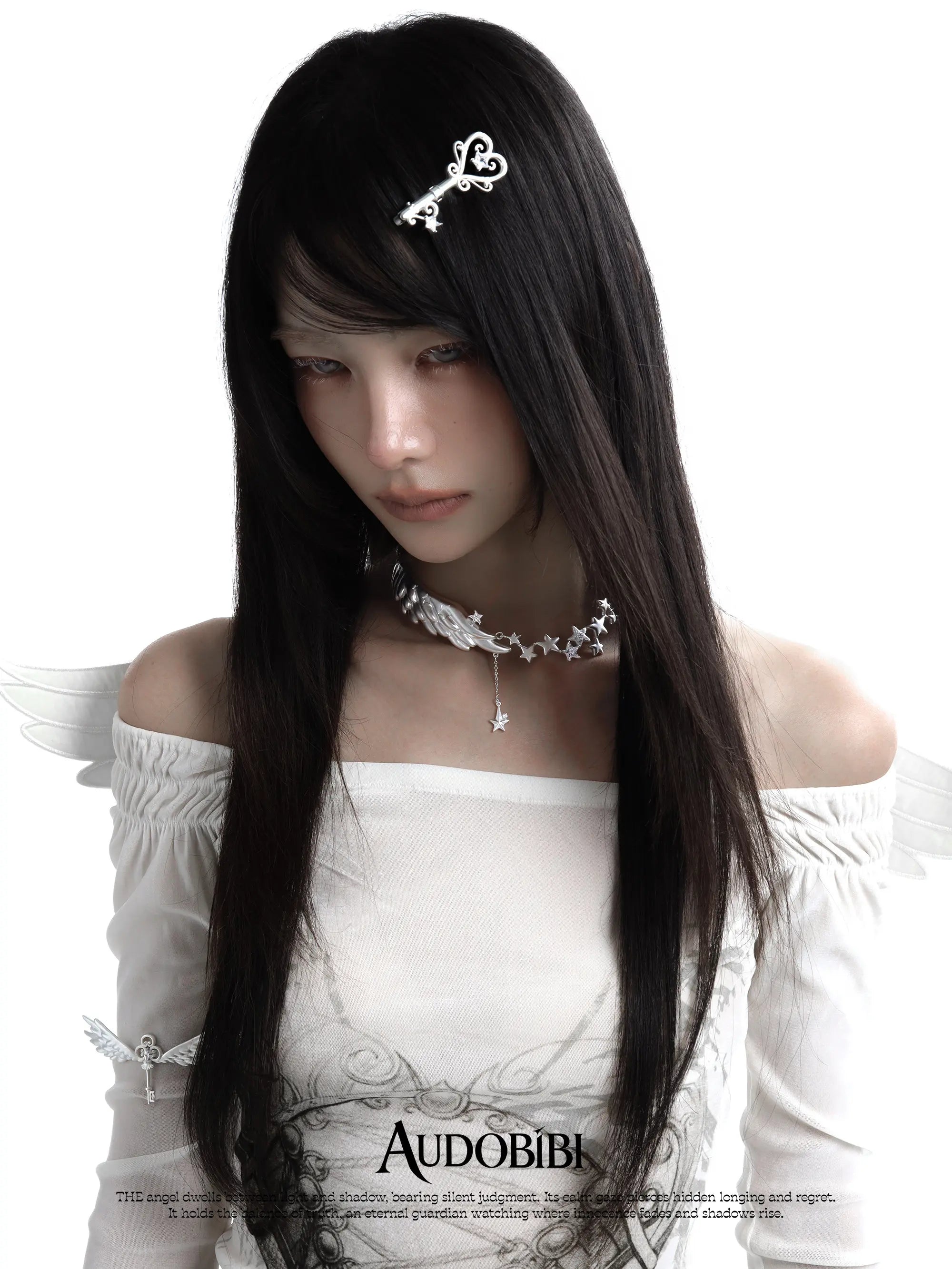 Wing-and-key arm cuff, worn with other jewelry in a model portrait.
