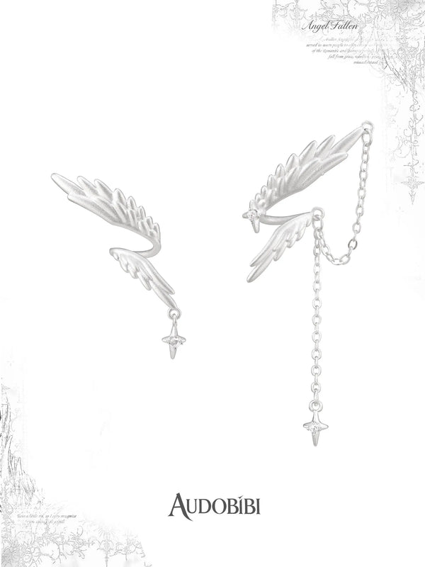 Asymmetric wing earrings with feather and chain drops on a white background.