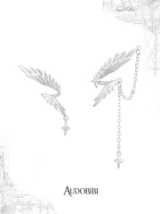 Asymmetric wing earrings with feather and chain drops on a white background.