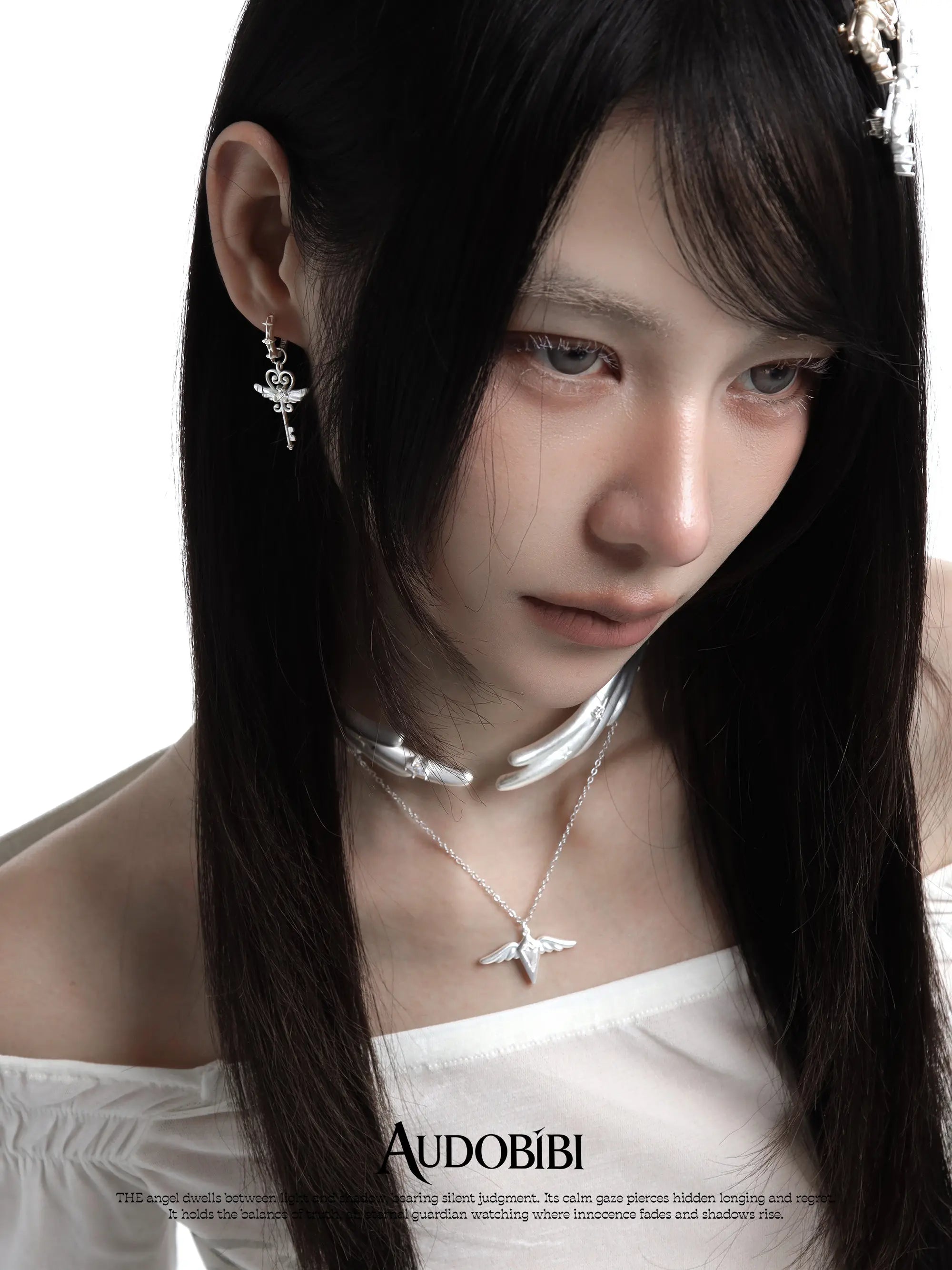 Wing choker with a draped chain, worn with other jewelry in a model portrait.