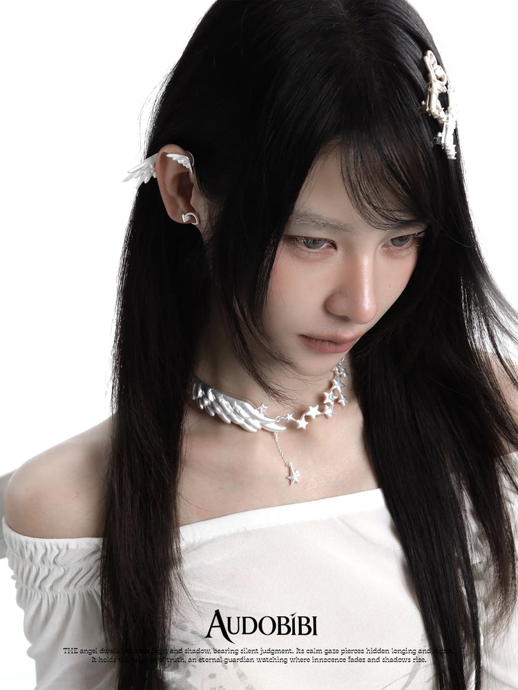 Wing-and-star necklace, worn with other jewelry in a model portrait.