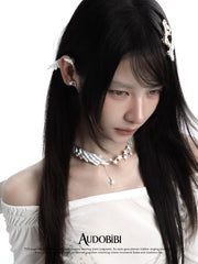 Wing-and-star necklace, worn with other jewelry in a model portrait.