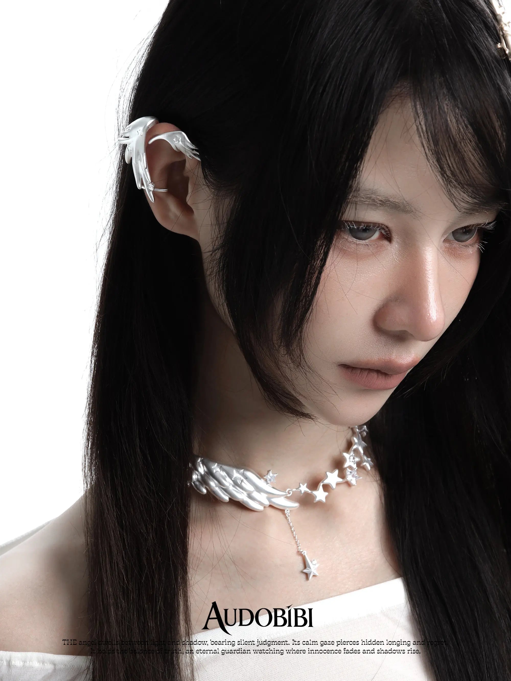 Wing-and-star necklace, shown in a close-up of the ear.