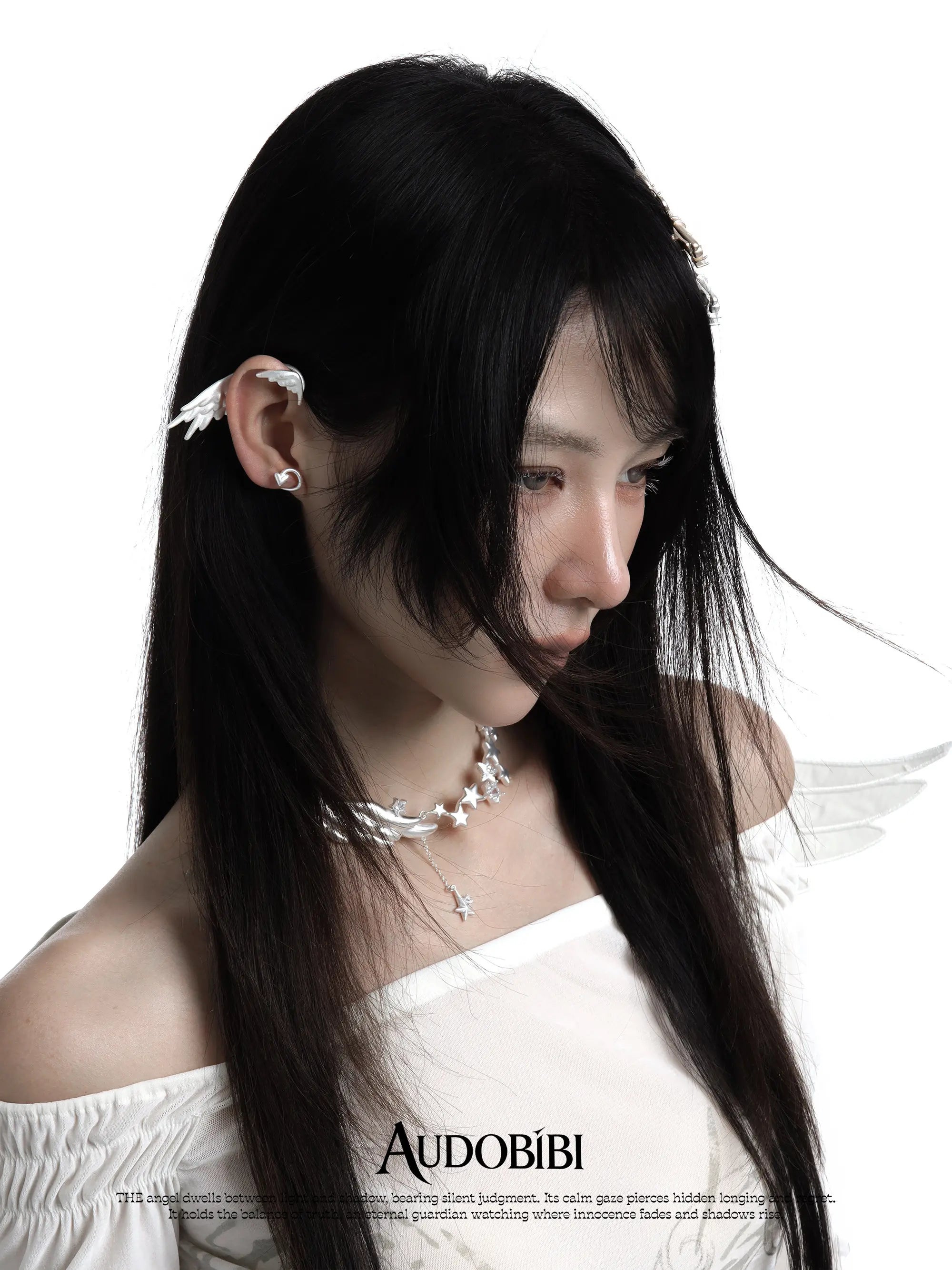 Wing-and-star necklace, worn with other jewelry in a model portrait.
