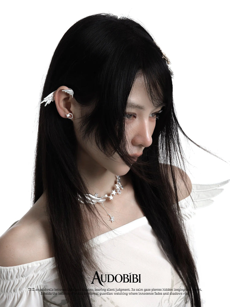 Wing-and-star necklace, worn with other jewelry in a model portrait.