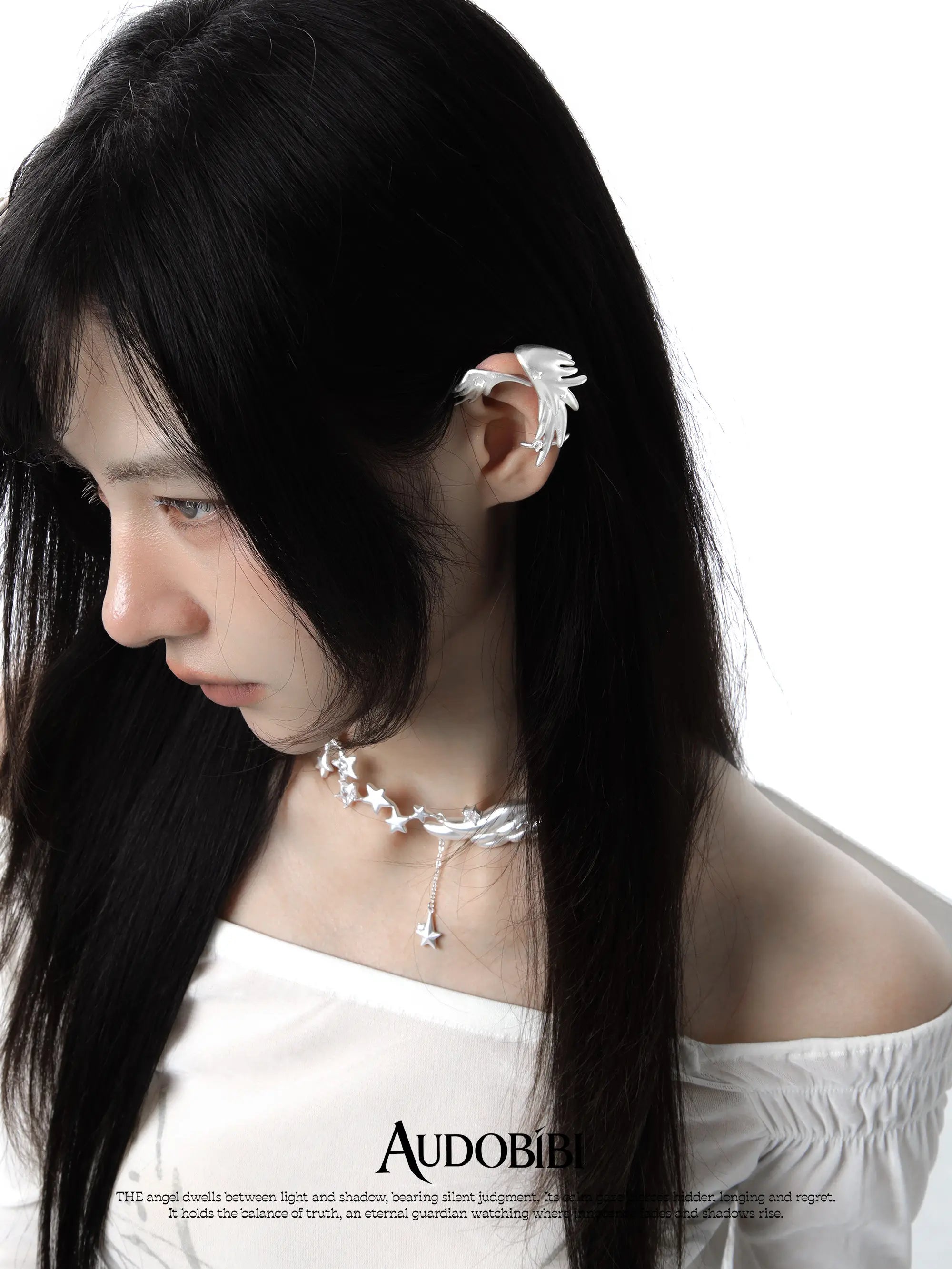 Wing-and-star necklace, worn with other jewelry in a model portrait.