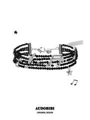 Multi-strand black bead bracelet with musical-note and star details.