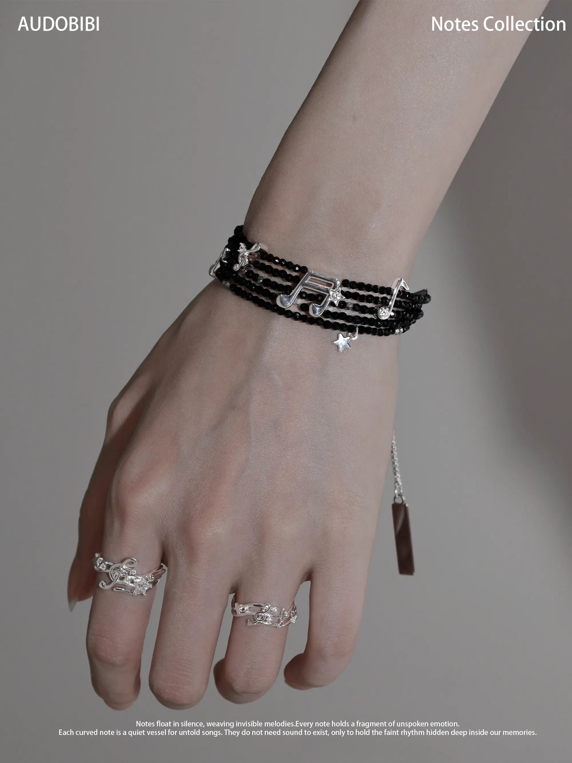 Black spinel musical-note bracelet, shown on the hand or wrist with other jewelry.