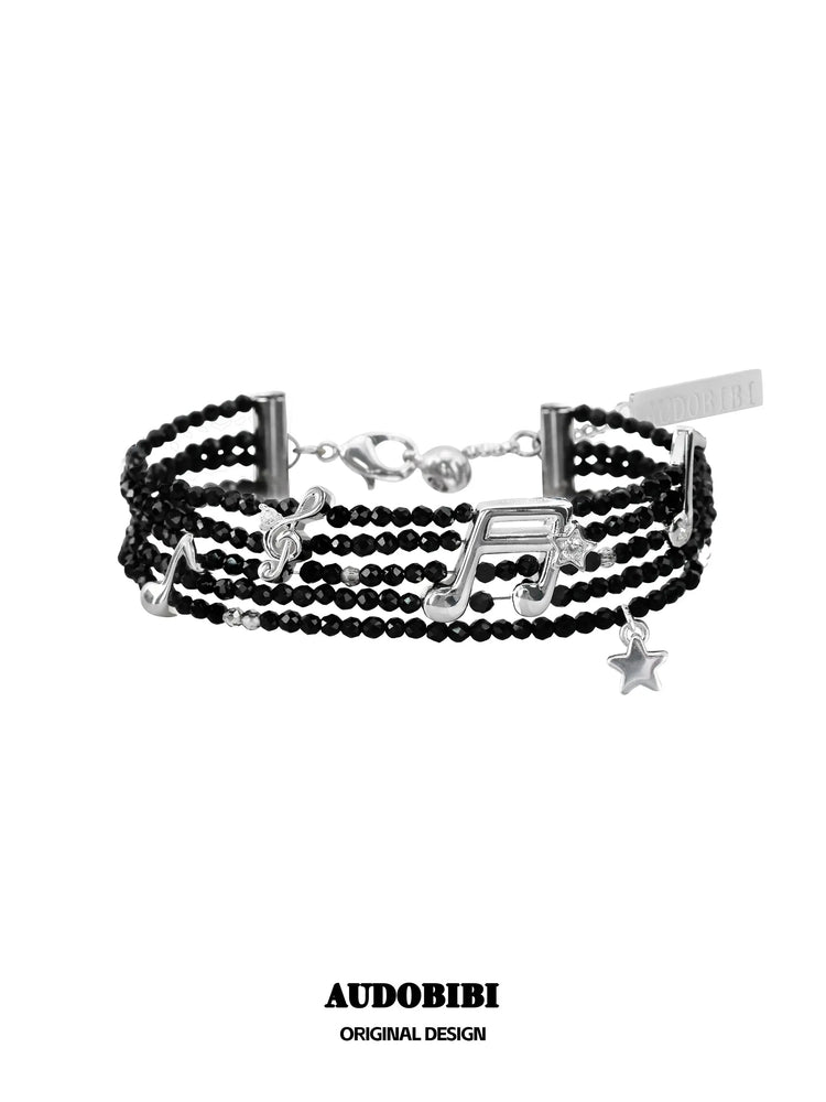 Black bead musical-note bracelet viewed from the front.