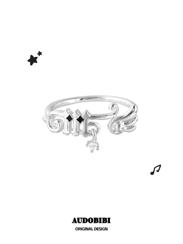Musical-note ring with a wing detail and small round drop, viewed from the front.