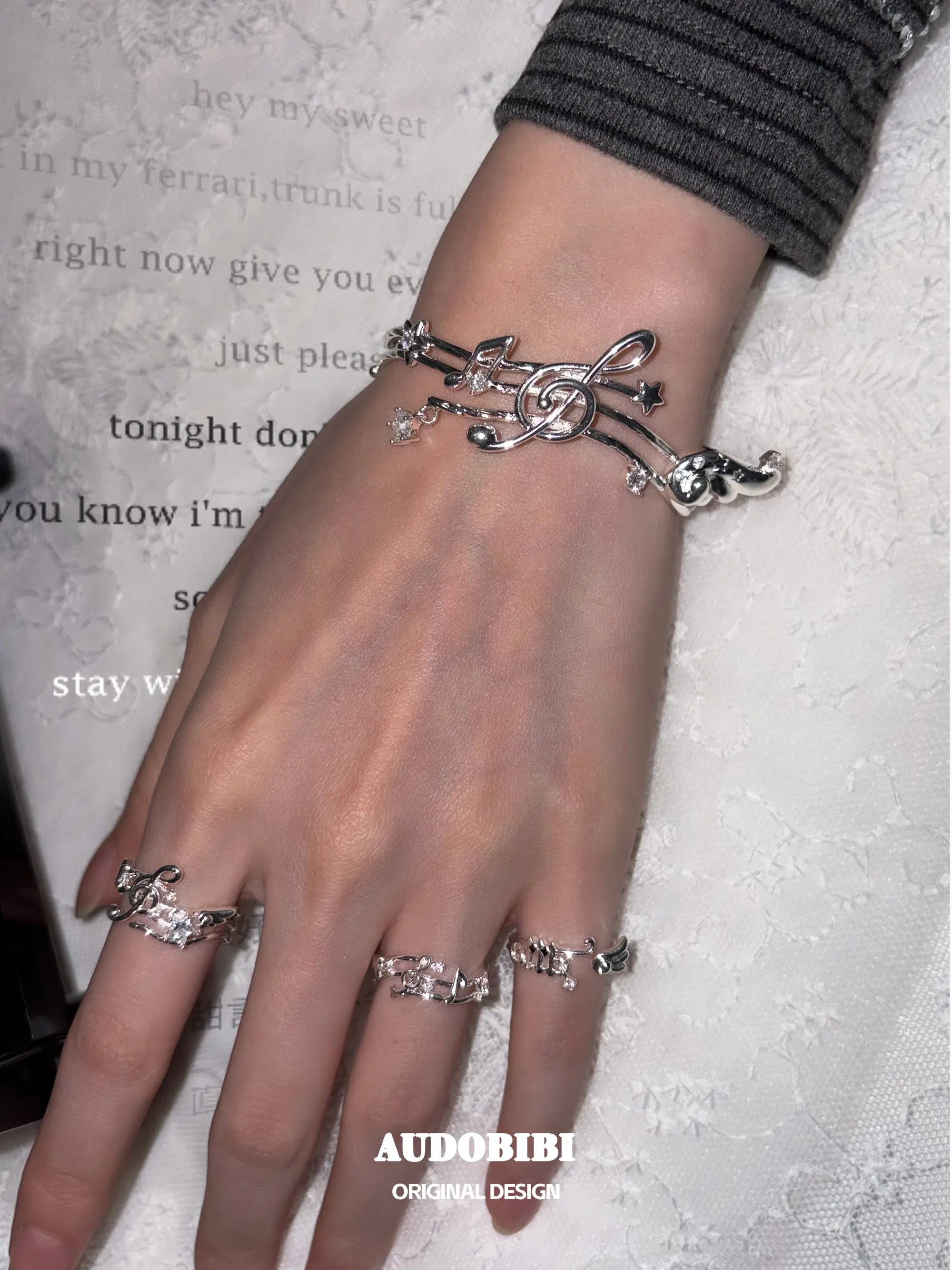 Musical-note pinky ring, shown on the hand or wrist with other jewelry.