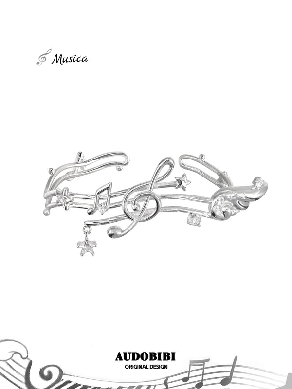 Open bangle shaped like a musical staff, with wing and hanging-star details.