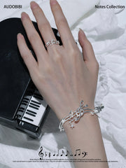 Musical-note open-ring designs, shown on the hand or wrist with other jewelry.